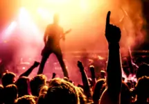 view from crowd cheering rock band performing on stage^ guitarist in silhouette