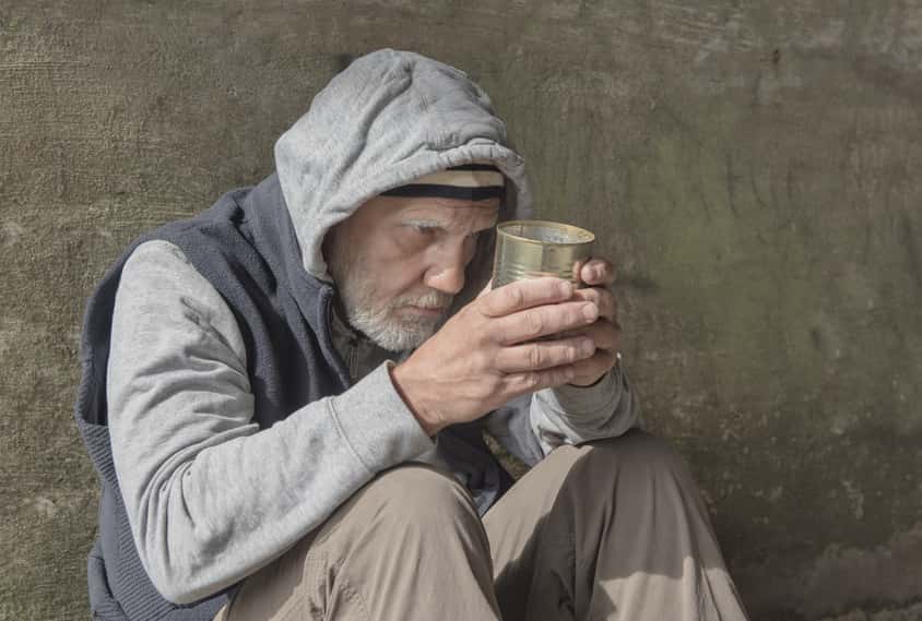portrait-image-of-a-mature-homeless-man-sitting-outdoors-with-a-tin-can