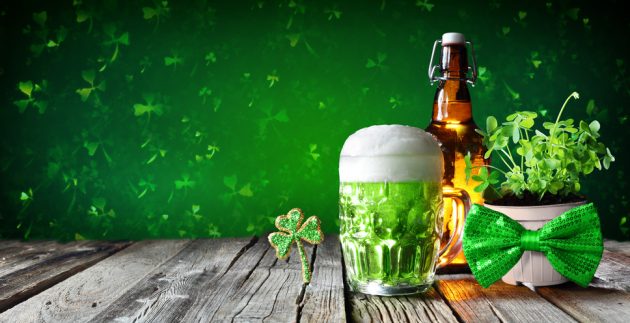 st-patricks-day-green-beer-in-glass-with-bottle-and-clovers-on-wooden-table