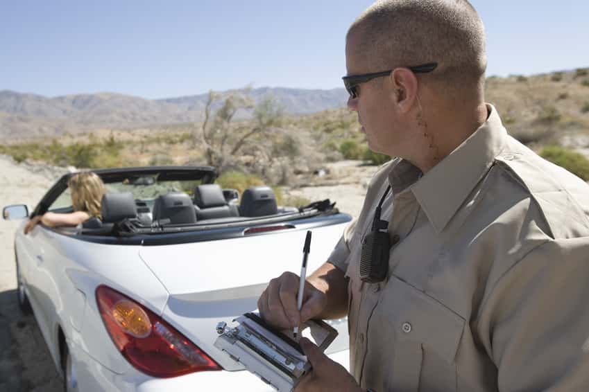 closeup-of-a-police-officer-writing-traffic-ticket-to-woman-sitting-in-car