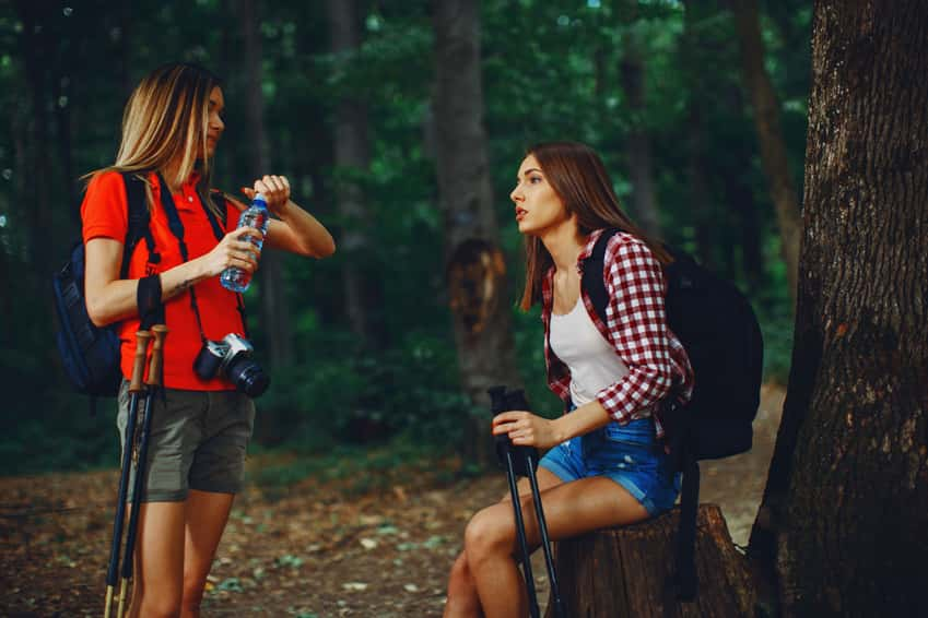 two-young-women-resting-after-hiking-in-the-woods