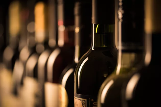 rowofvintagewinebottlesinawinecellarshallow