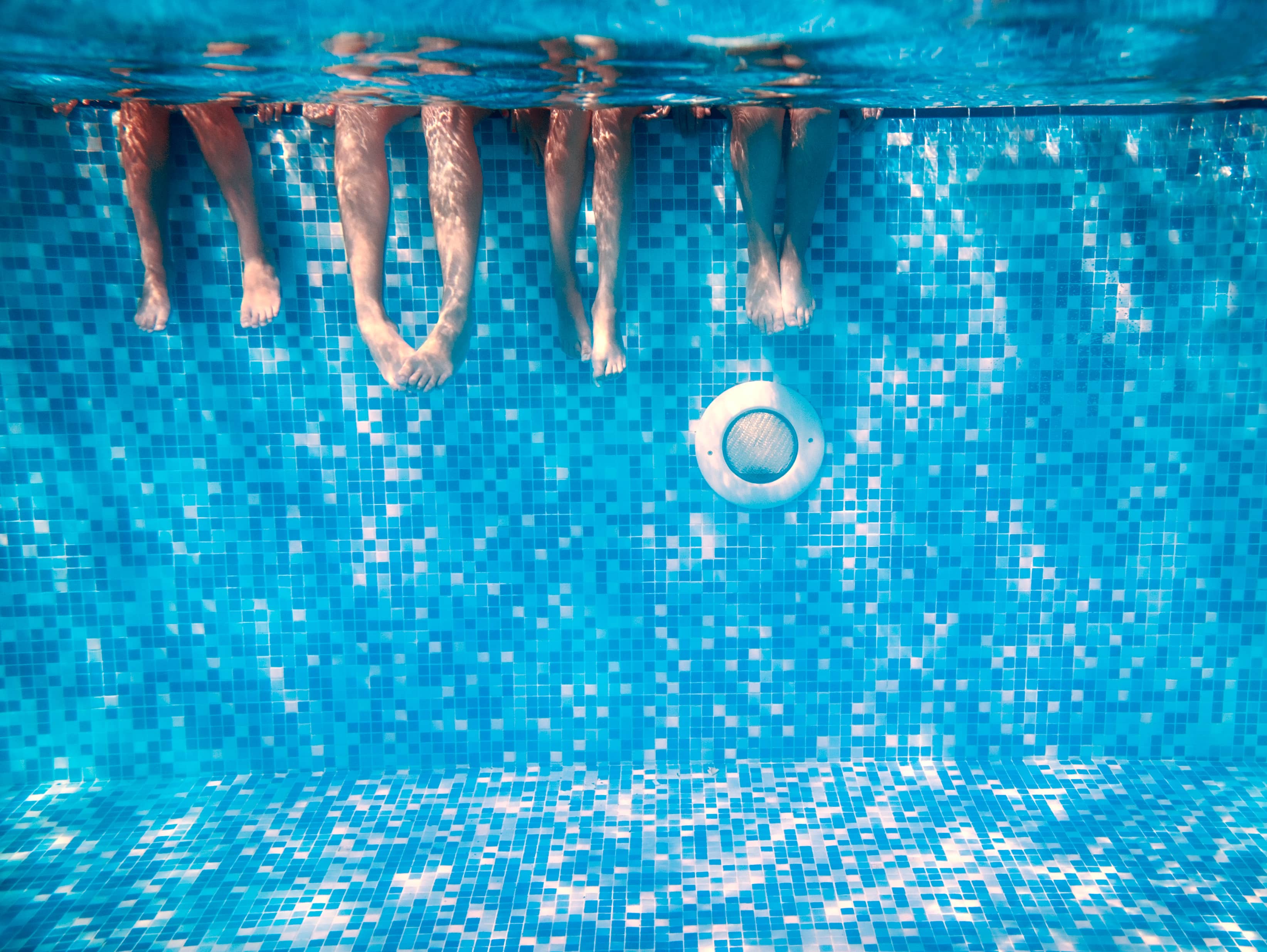 childrensandadultslegsunderwaterintheswimmingpool