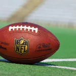 Official ball of the NFL football league on grass turf background.