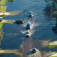 Flooded road in Florida after heavy hurricane rainfall. Aerial view of evacuating cars and surrounded with water houses in suburban residential area