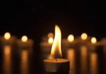 Burning candles. The candles burn against a black background and the flames move when the wind blows. The concept of a memorial day. Background for advertising and design projects.