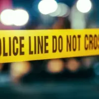 Yellow Tape Showing Text "Police Line Do Not Cross" Restricting a Crime Scene Area At Night. Close Up Aesthetic Shot with Bokeh Effect and Flickering Lights. Criminal on the Loose Strikes Again