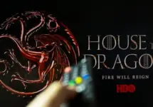 House of the Dragon HBO TV series on TV with remote control in hand. Focuse on the tv screen. Story takes place 300 years before events portrayed in Game of Thrones