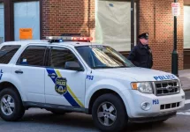 A uniformed Philadelphia Police officer stands beside a police vehicle. PHILADELPHIA^ PA - JANUARY 1^ 2015