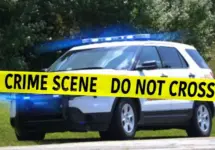 Sheriff Department vehicle with emergency lights on behind Crime Scene tape