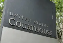 The United States Courthouse sign stands tall amidst a serene backdrop of trees at the US District Court in Seattle^ Washington. Seattle - May 17^ 2019: