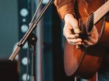 close up of hand of man playing guitar in concert on stage