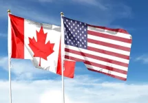 USA and Canada flags against cloudy sky. waving in the sky