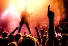 view from crowd cheering rock band performing on stage^ guitarist in silhouette