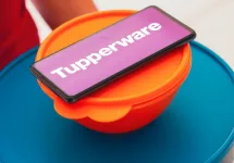 In this photo illustration^ a person carries various plastic products (containers) and a smartphone shows the Tupperware logo