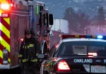 A firefighter stands outside a blaze at a transfer station in East Oakland. Two RVs caught fire in the enclosed lot. Oakland^ California - April 18^ 2026
