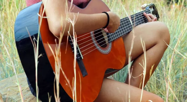 female country artist playing guitar outdoors