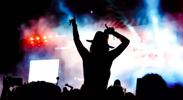 femela concertgoer in silhouette in front of stage lights^ watching show