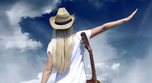 Young woman with guitar on the road and her vintage baggage