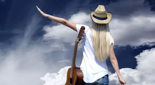 Young woman with guitar on the road and her vintage baggage