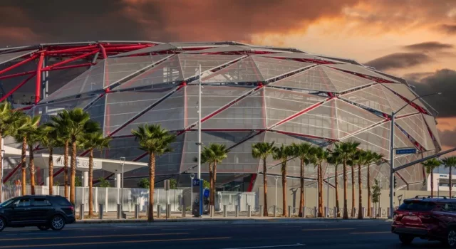 The Intuit Dome with cars driving on the street^ lush green palm trees and powerful clouds at sunset in Inglewood California USA. Inglewood^ California USA - 10 22 2024