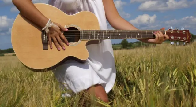 Country girl with guitar at wheat field