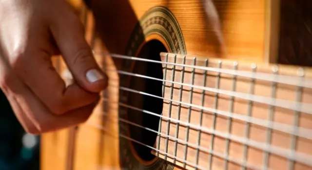 A woman plays an acoustic guitar.
