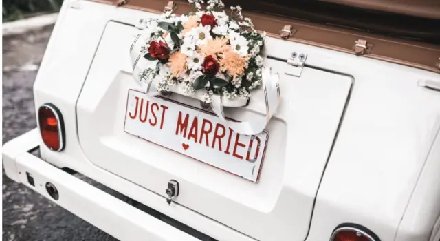 'JUST MARRIED" sign with flower decoration on white wedding car
