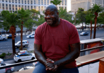 shaq-sitting-on-a-balcony-above-a-busy-street-png-2