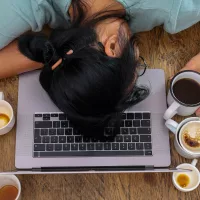 exhaustedfemaleworkersurroundedbycoffeecupssleepingatworkplace