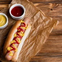 delicioushotdognearbowlswithsaucesandcrumpledkraft