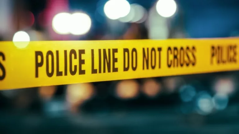Yellow Tape Showing Text "Police Line Do Not Cross" Restricting a Crime Scene Area At Night. Close Up Aesthetic Shot with Bokeh Effect and Flickering Lights.