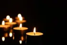 Burning candles on mirror surface in darkness^ closeup