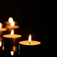 Burning candles on mirror surface in darkness^ closeup