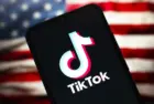TikTok logo is seen displayed on a smartphone screen and in the background^ the United States flag^ in Reno^ United States^ on January 15^ 2025 In this photo illustration^ the TikTok logo is seen displayed on a smartphone screen and in the background^ the United States flag^ in Reno^ United States^ on January 15^ 2025