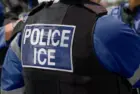 ICE police agent - Officer of Immigration and Customs Enforcement. Close-up of POLICE ICE marking on the back of a stab proof vest uniform worn by a trio of police officers at the scene of an immigrant incident. The ICE federal law enforcement agency is under the supervision of the United States Department of Homeland Security.
