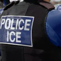 ICE police agent - Officer of Immigration and Customs Enforcement. Close-up of POLICE ICE marking on the back of a stab proof vest uniform worn by a trio of police officers at the scene of an immigrant incident. The ICE federal law enforcement agency is under the supervision of the United States Department of Homeland Security.