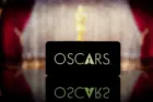 A smartphone displaying the Oscars logo against a blurred awards ceremony background. January 13^ 2025