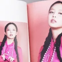 Fan hands holding BlackPink BORN PINK 2nd Album photobook with Jennie on grey. Pink music CD in player. South Korean girl group BlackPink