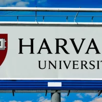 billboard displaying logo of Harvard University^ a private Ivy League research university in Cambridge^ Massachusettsl