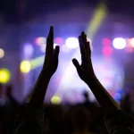 woman claps his hands at a musical concert in a crowd of people. clapping crowd at singer's concert. smoke^ applause and hands in soft focus^ abstract background