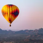 Hot air balloon flies over phoenix^ Arizona with Sonoran Desert in background