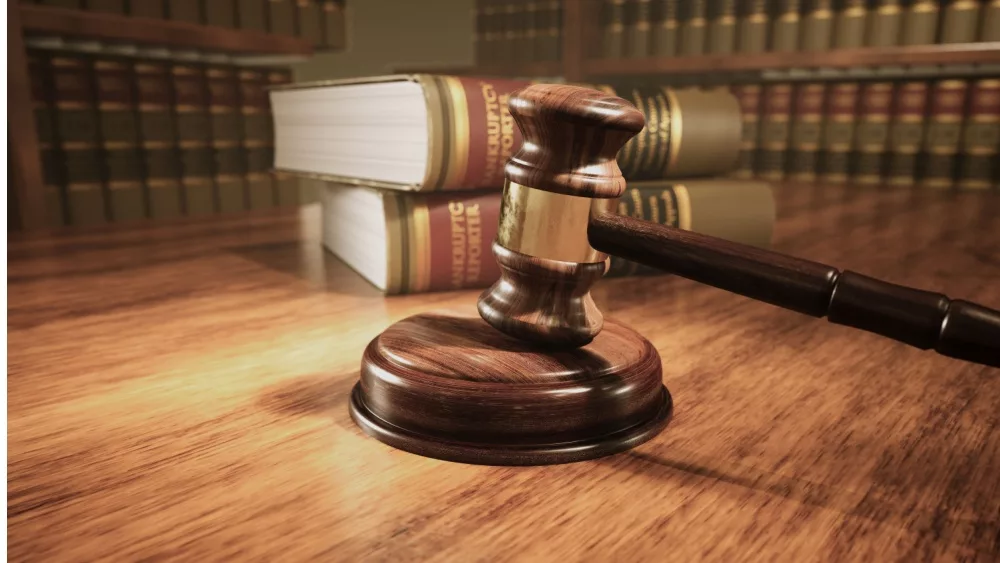 Wooden gavel on the judge's bench with a backdrop of law books