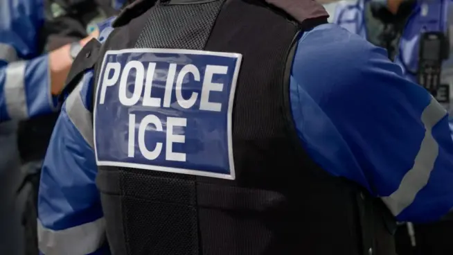 ICE police agent - Officer of Immigration and Customs Enforcement. Close-up of POLICE ICE marking on the back of a stab proof vest uniform worn by a trio of police officers at the scene of an incident