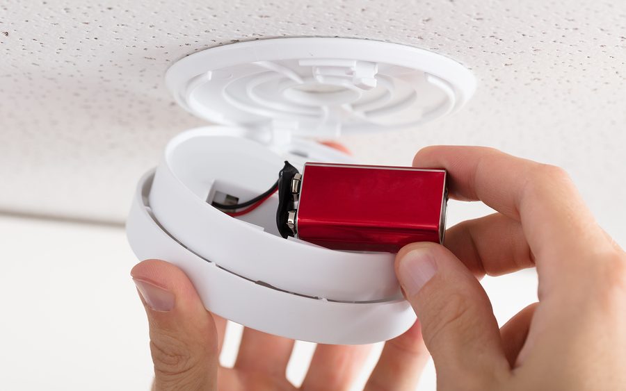 close-up-of-a-persons-hand-inserting-battery-in-smoke-detector