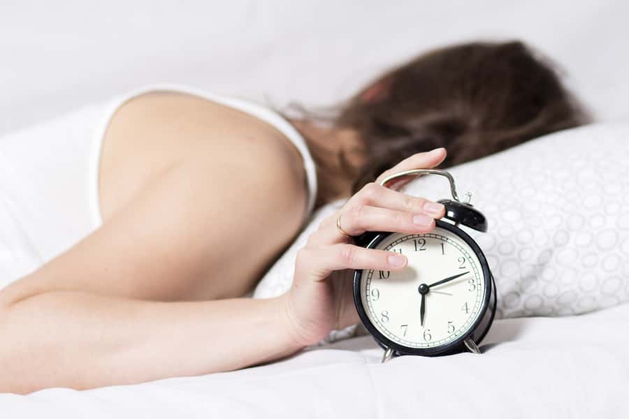 girl-is-sleeping-on-bed-in-bedroom-and-turns-off-alarm-clock-wo