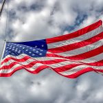 american-flag-at-half-mast-or-half-staff-blowing-in-wind-with-bl