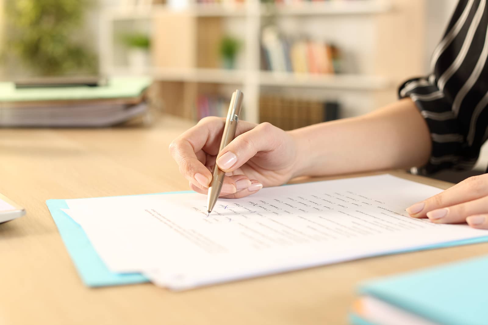 close-up-of-woman-hands-filling-out-form-working-sitting-on-a-de