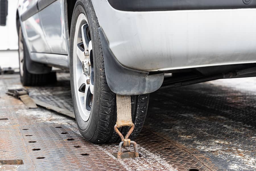 close-up-of-car-wheel-tied-with-safety-harness-on-flatbed-tow-tr