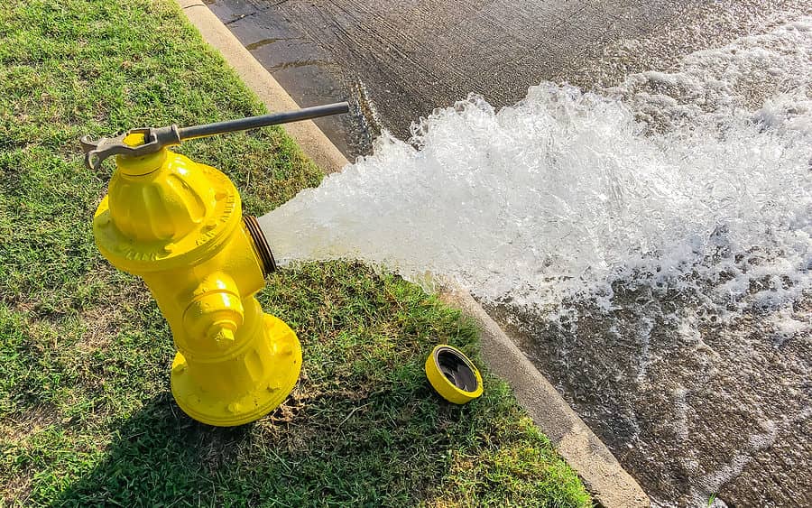 top-view-yellow-fire-hydrant-gushing-water-across-a-residential